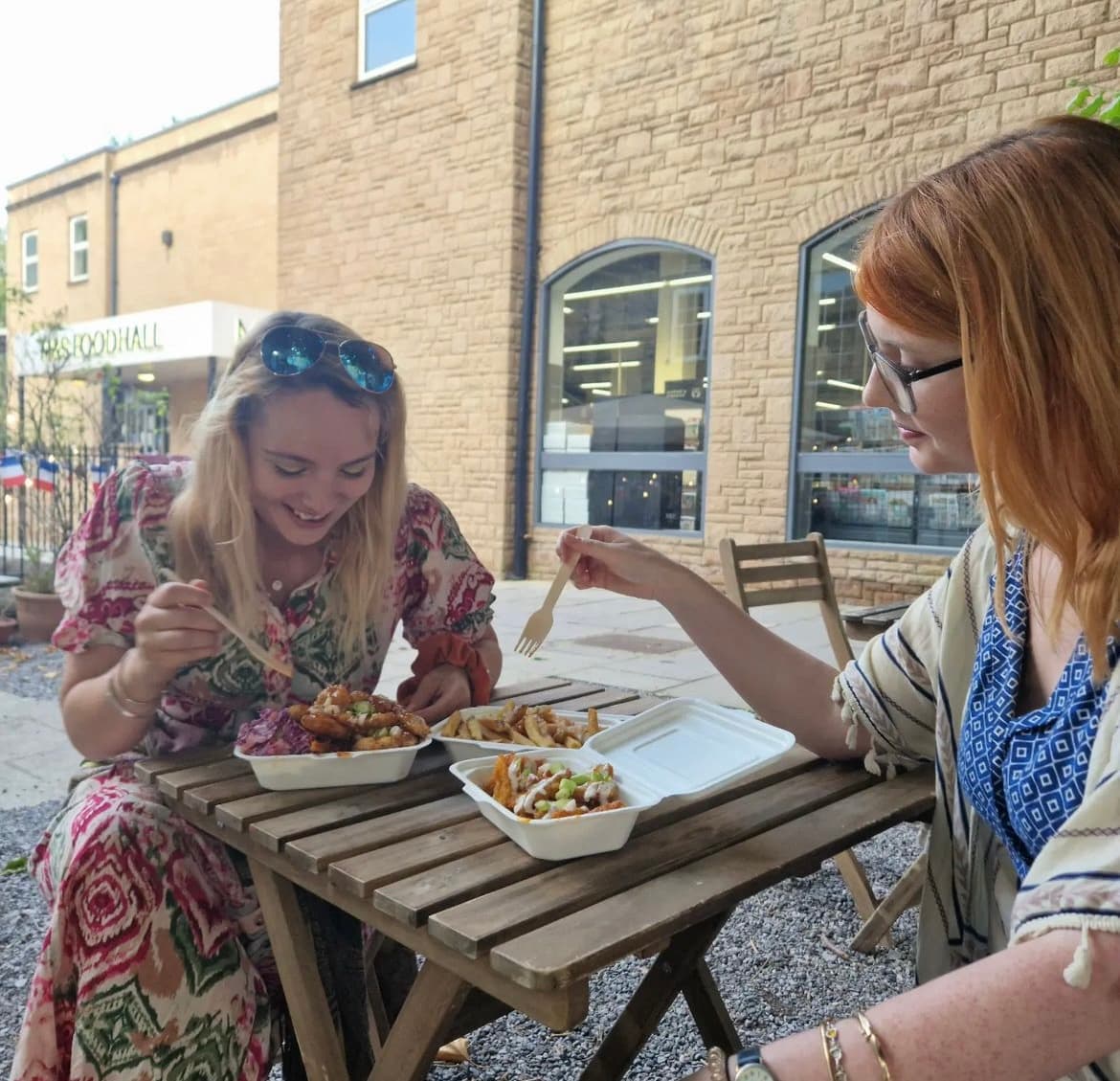 Two happy customers eating chubby vegans food on site in Frome.